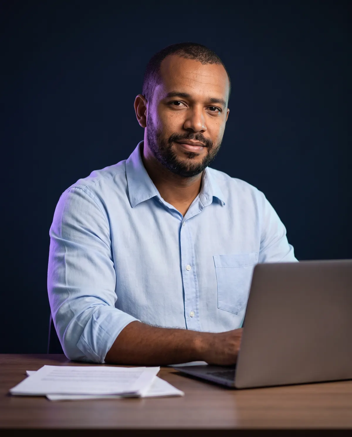 Contador sorrindo em sua mesa, com notebook e documentos, pronto para usar o certificado e-CNPJ da empresa